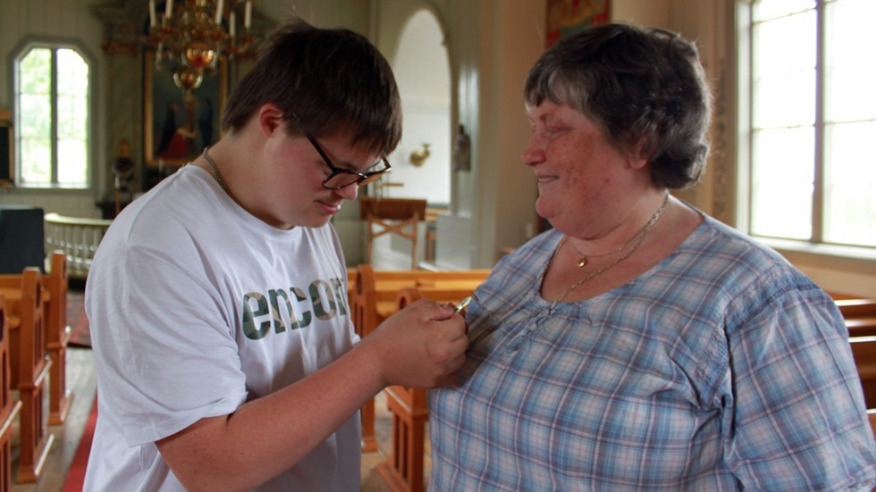 Oliver tar en titt på Britt Anderssons diakonsmycke. Runt halsen hänger guldsmycket hon fick på sin egen konfirmation. "Jag har önskat mig ett guldkors", säger Oliver.