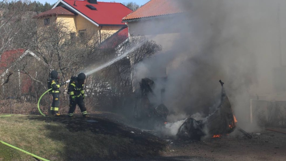 Brandmännen sprutar vatten på resterna av husbilen.