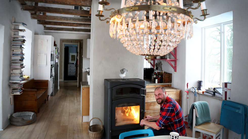 Under kökets grova takbjälkar lägger Petter Schwan en brasa. Vedeldning kompletterar golvvärmen som finns i hela huset, som på årsbasis är helt självförsörjande på el från solen.