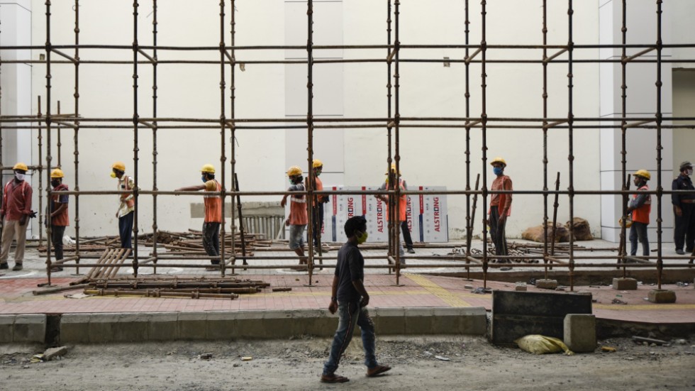 Indiska arbetare iklädda mask vid ett tunnelbanebygge i Kochi, i den Indiska delstaten Kerala. Migrantarbetare och dagavlönade arbetare, som ofta missas i statistiken lider hårt av pandemin och restriktionerna de medför.
