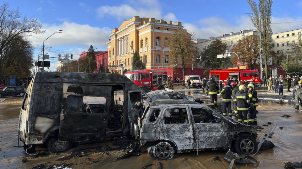 Räddningsarbetare intill utbrända bilar i centrala Kiev.