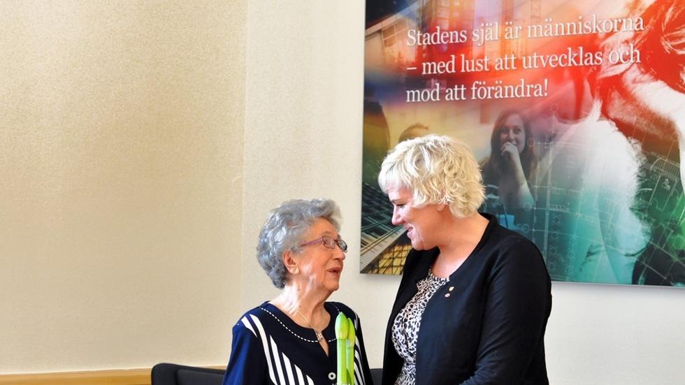 Kristina Edlund delar ut blomma och bjuder in Irena till kommunfullmäktiges traditionsenliga middag. Foto: Tommy Pettersson