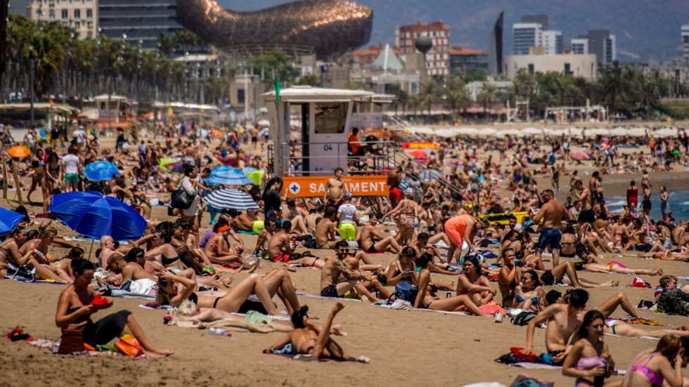 Solbadare på stranden i Barcelona. Den för landet så viktiga turismen spås nu drabbas av den nya virusvågen.